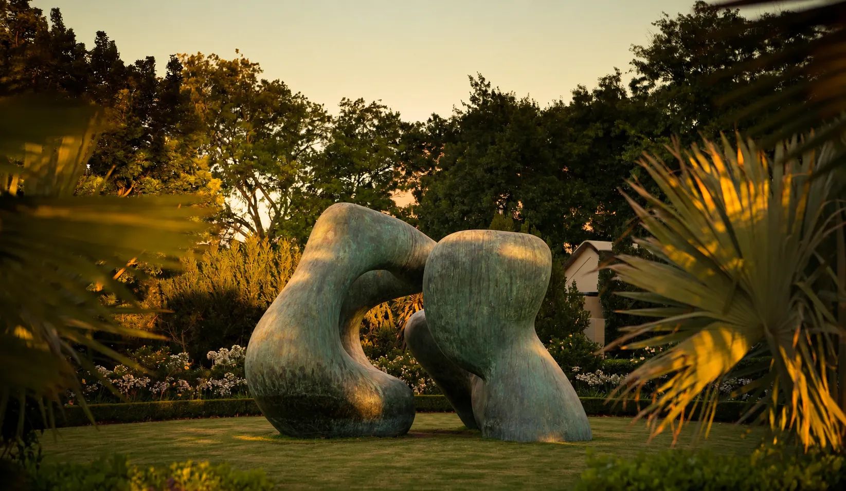 A large bronze sculpture in a garden at dusk